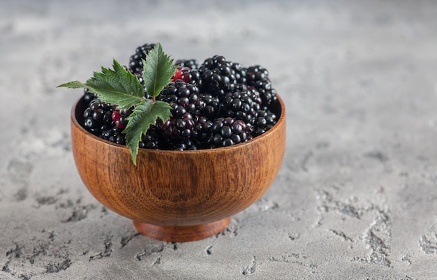 Blackberries in a wooden bow. Ripe and tasty black berry isolated on white.