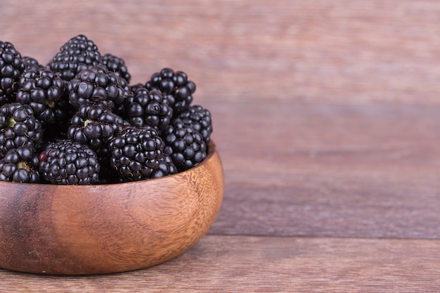 Blackberries in wooden bowl on white background