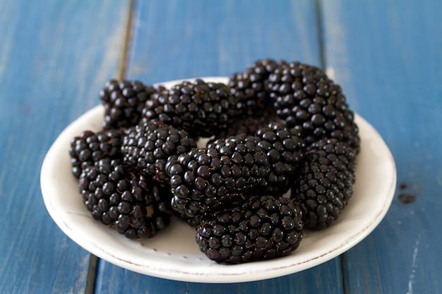 Blackberry on dish on blue wooden surface