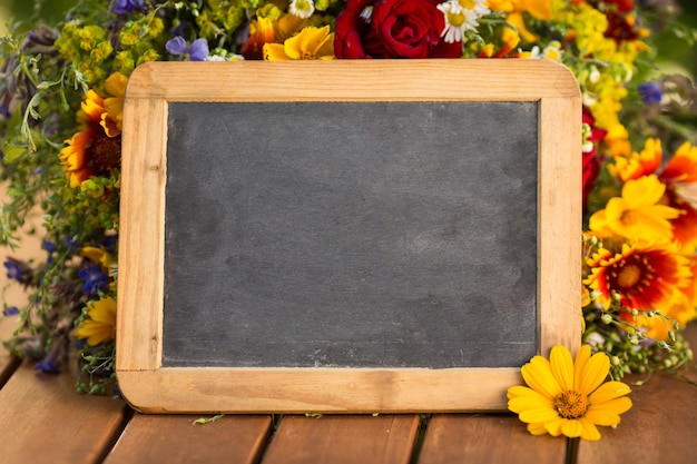 Blackboard blank and flowers on wooden table