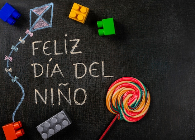 Blackboard geschreven feliz dia del niÃ ± o (spaans). Vliegerontwerp met assemblagestukken en lolly
