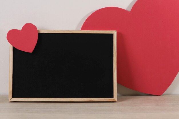 Blackboard and hearts on wooden table