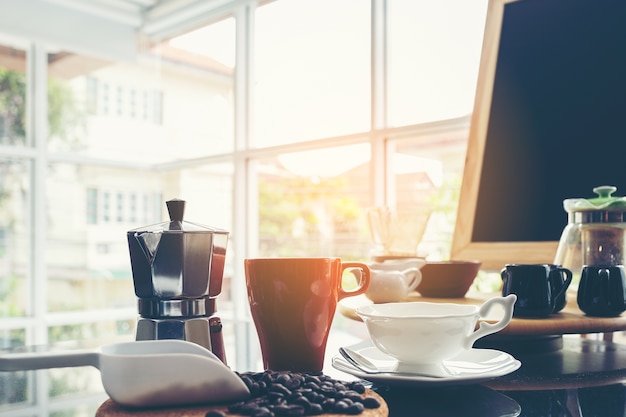 Menu della lavagna sul piano d'appoggio di legno di marrone scuro con la tazza di caffè alla caffetteria della finestra