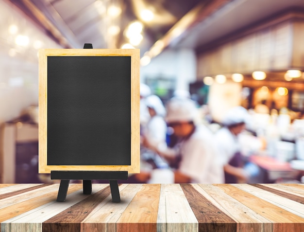 Blackboard menu with easel on wooden table with blur open kitchen