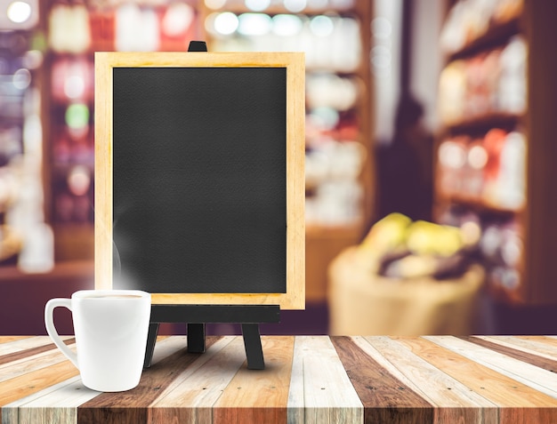 Foto menu della lavagna con il cavalletto sulla tavola di legno con la tazza di caffè al fondo del caffè della sfuocatura