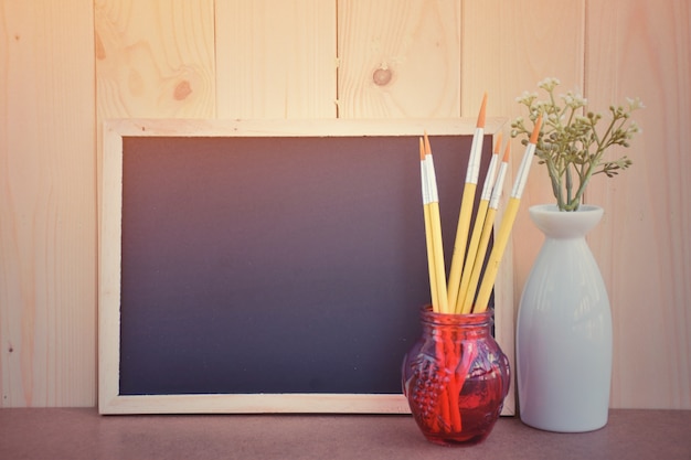the blackboard and paint brush on wooden table