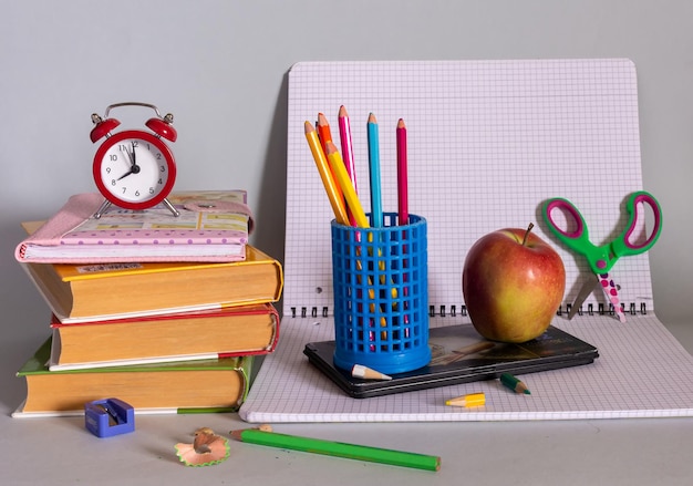 Blackboard, textbooks, notepads, pencils, a globe and an apple