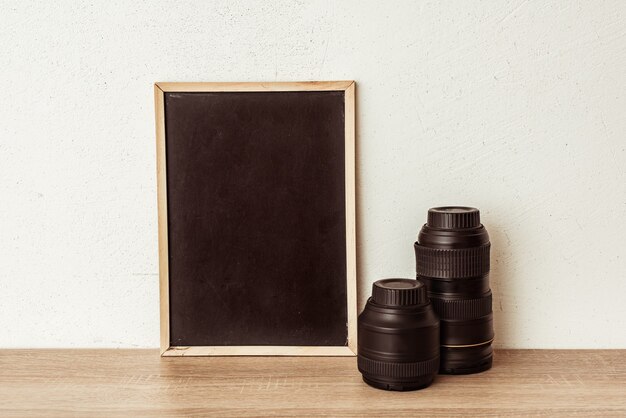 blackboard with camera lenses on a wooden shelf. place for inscription, an advertising concept for a photo school
