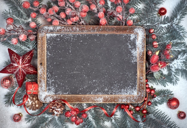 Photo blackboard with christmas decorations on snow, space