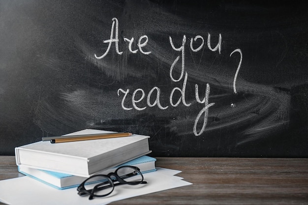 Blackboard with question Are you ready and notebooks on table Preparing for exam