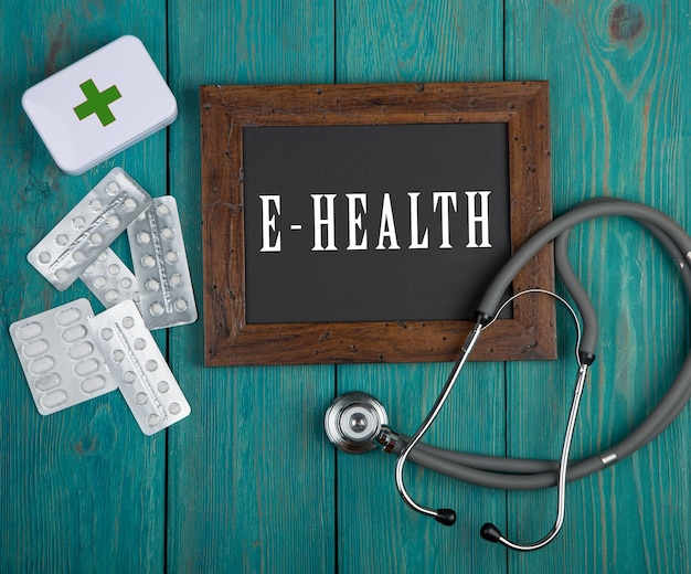 Доска с текстом Ehealth и стетоскоп на синем деревянном фоне