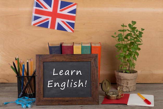 Blackboard with text Learn English flag of the United Kingdom books pencils compass