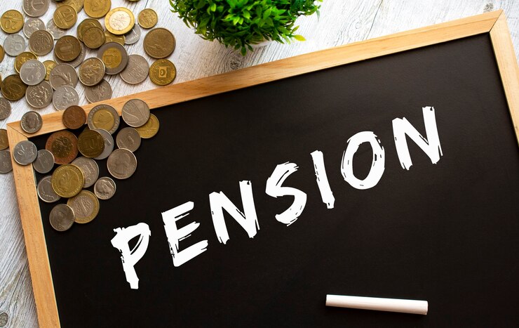 灰色の木製テーブルにPENSIONと金属コインのテキストが書かれた黒板