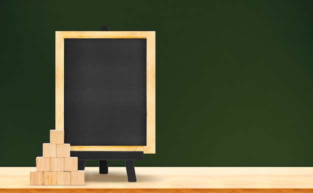 Blackboard and wood cube on wood table on dark green background