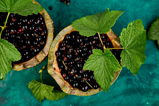 Blackcurrant berries with leaves, black currant in green bowls.