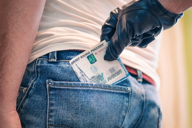 Photo a blackgloved hand pulls the money out of his back pocket the concept of petty crime and theft committing a crime stealing money from the back of your jeans pocket closeup