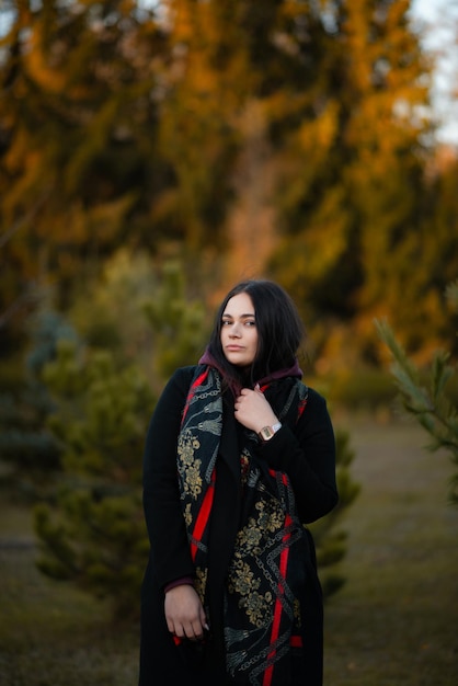 Photo blackhaired girl in a black coat in autumn in the park