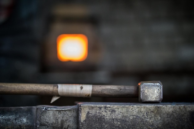 Blacksmith and anvil blacksmith working with metal workpiece of new hammer on the anvil at the forge