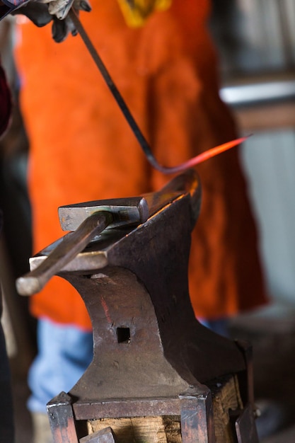 Blacksmith bending hot iron on the anvil.