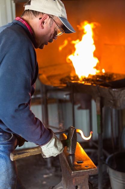 Blacksmith bending hot iron on the anvil.