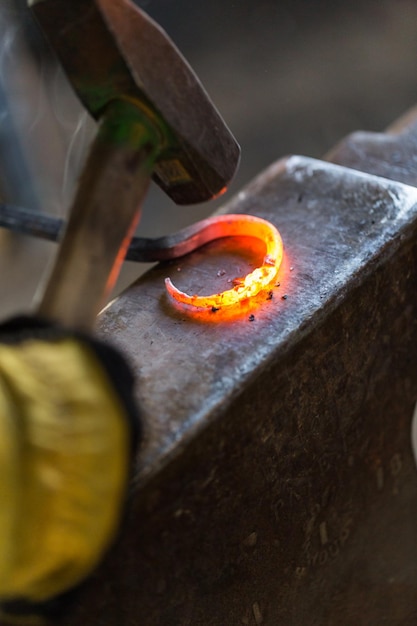 Blacksmith bending hot iron on the anvil.