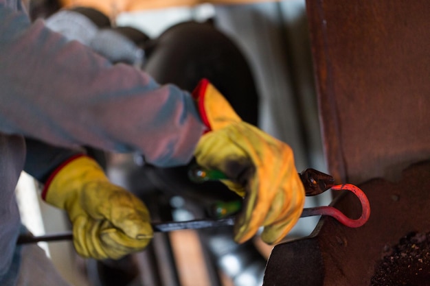 Blacksmith bending hot iron on the anvil.