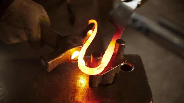 Photo blacksmith bending a longer piece of hot metal in a knife handle