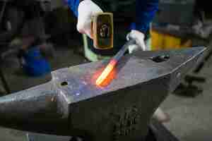 Photo the blacksmith forges the luminous metal in the furnace, kicks out the sparks