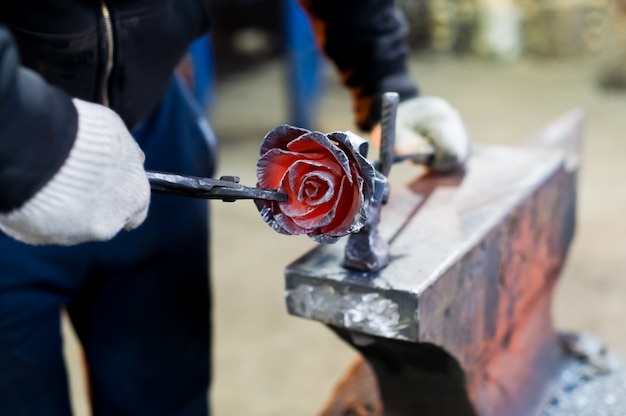 Blacksmith forges steel rose on the anvil