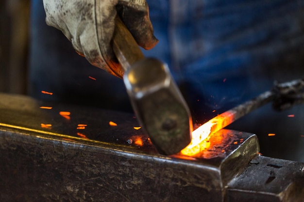 A blacksmith forging hot iron on the anvil.