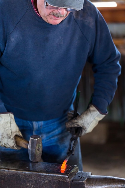 Photo a blacksmith forging hot iron on the anvil.