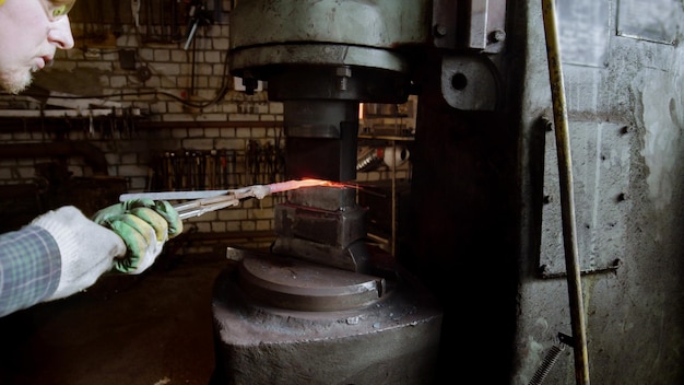 Blacksmith forming a knife using an industrial pressure machine