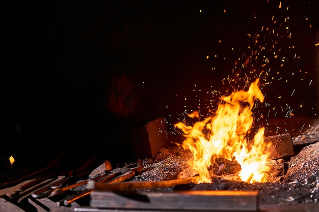 Blacksmith furnace inner space with burning fire and forging tools lying nearby