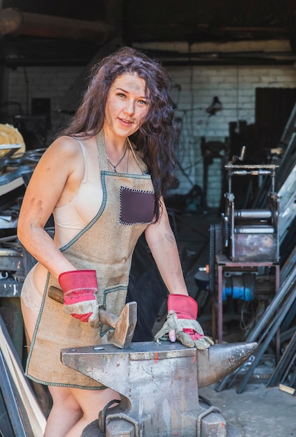 Blacksmith girl in the workshop near the anvil