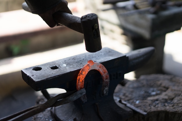 Photo a blacksmith makes a horseshoe with a hot iron.