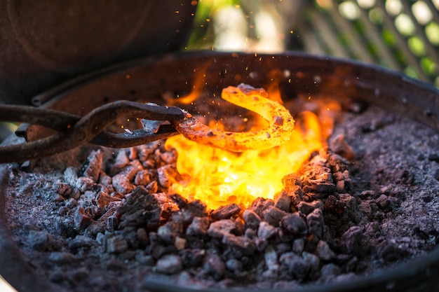 Blacksmith making a horseshoe in small forge.