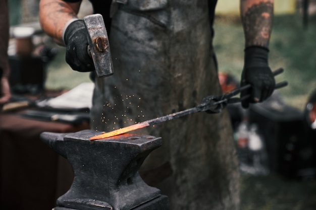 Photo blacksmith manually forging molten metal on anvil