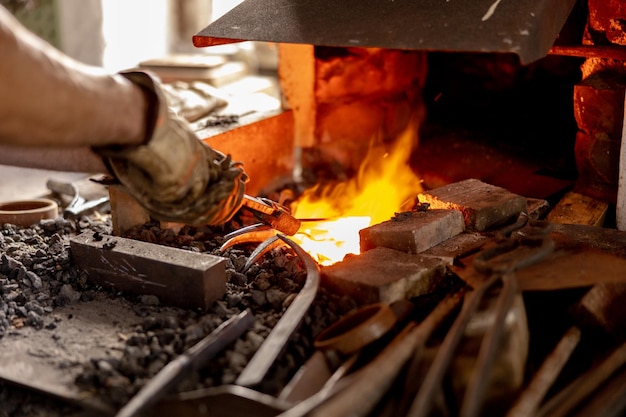 The blacksmith in production process of metal products handmade in the forge Craftsman heats metal in the fire Metal industry old profession