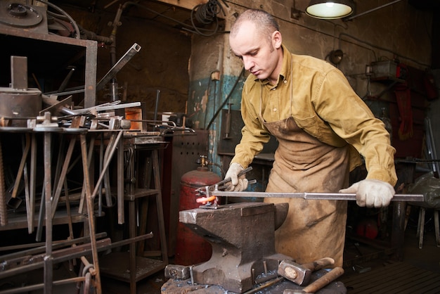 The blacksmith in the production process of metal products handmade in the workshop