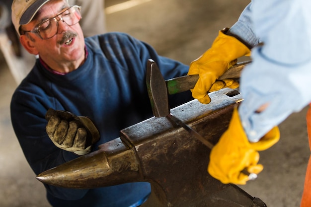 A blacksmith teaching his students to old craft.