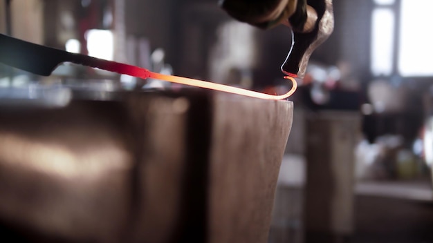 Blacksmith torque the longer piece of metal in a spiral using a hammer