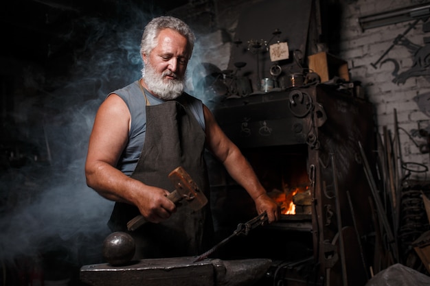 Photo blacksmith with brush handles molten metal