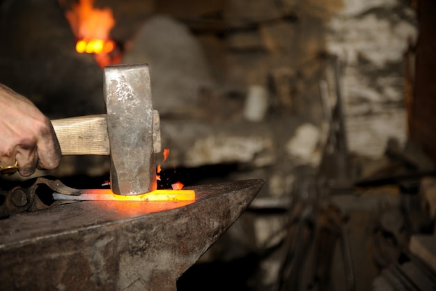 Blacksmith working in the forge processes the metal . The photograph on the subject of blacksmithing