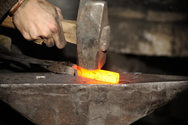 Blacksmith working in the forge processes the metal The photograph on the subject of blacksmithing