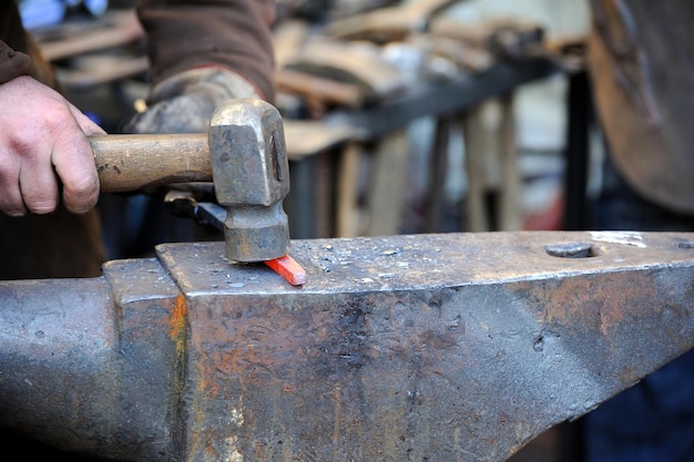 Blacksmith working metal with hammer on the anvil in the forge