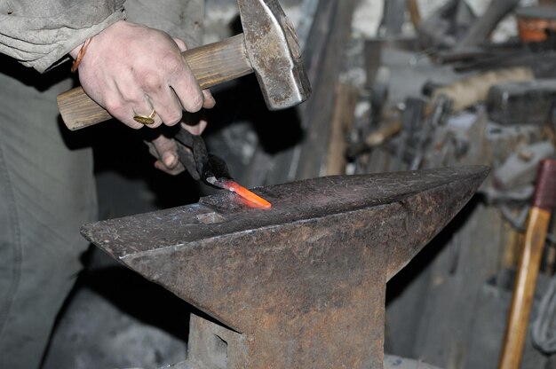 Blacksmith working metal with hammer on the anvil in the forge