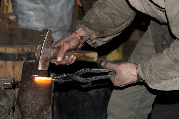 Blacksmith working metal with hammer on the anvil in the forge