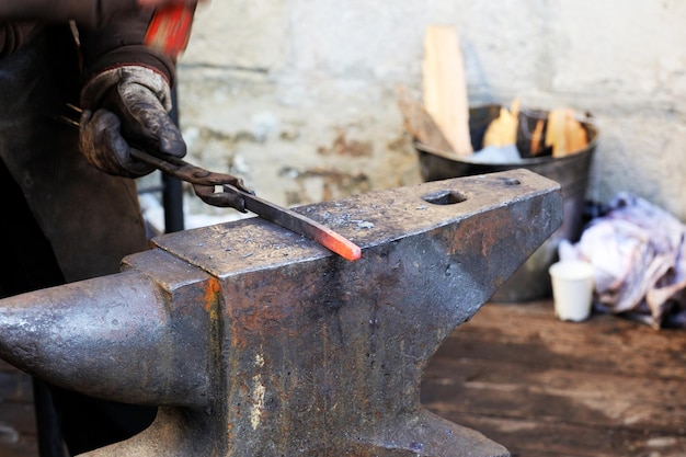 Blacksmith working metal with hammer on the anvil in the forge