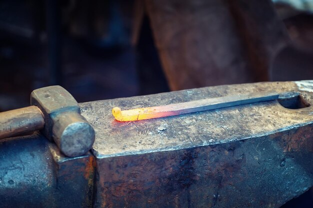 Blacksmith working metal with hammer on the anvil in the forge