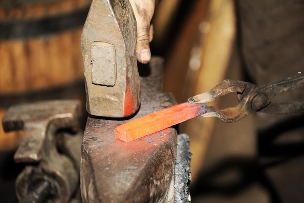 Blacksmith working metal with hammer on the anvil in the forge